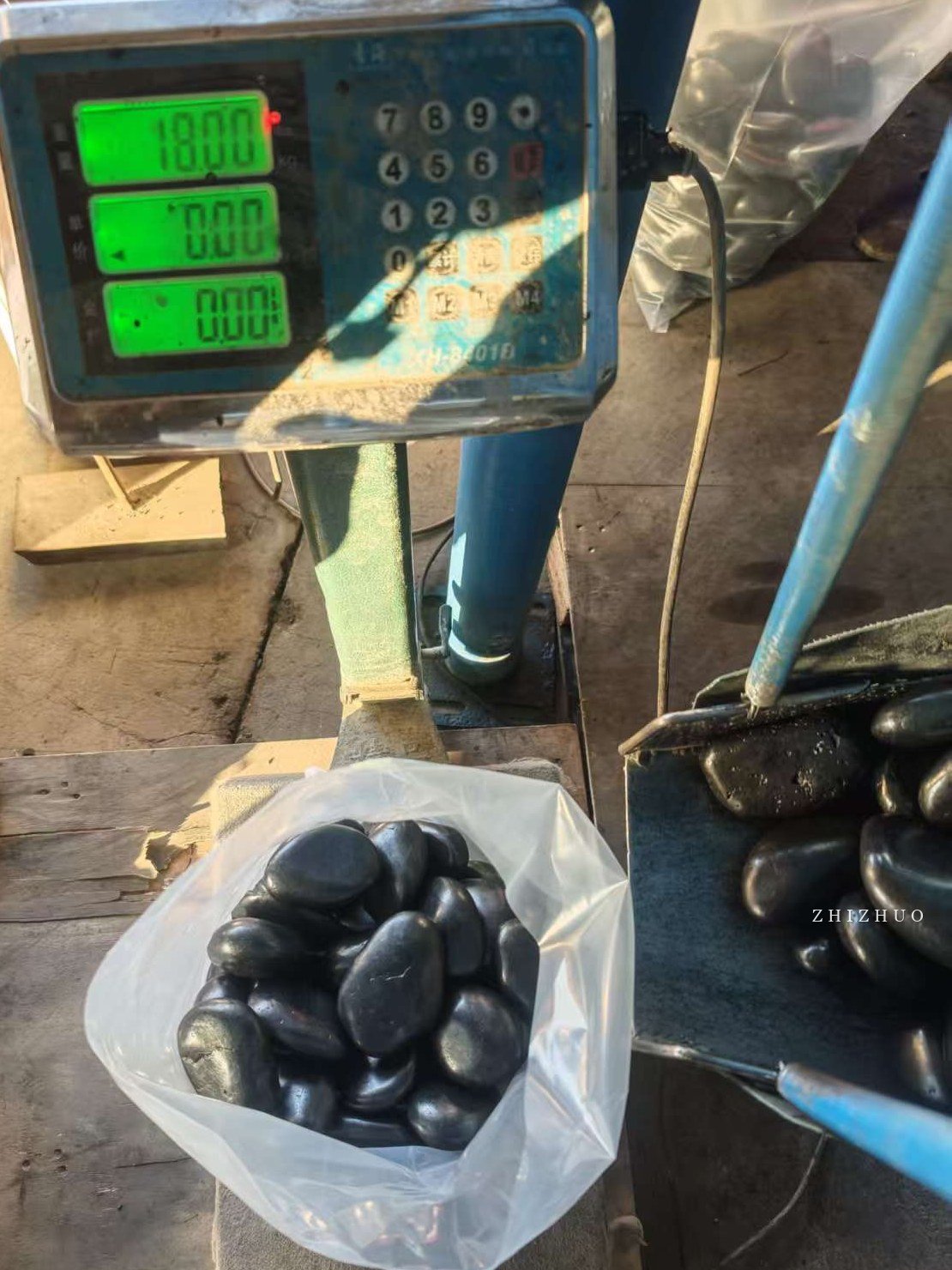 Black polished pebbles being weighed before export