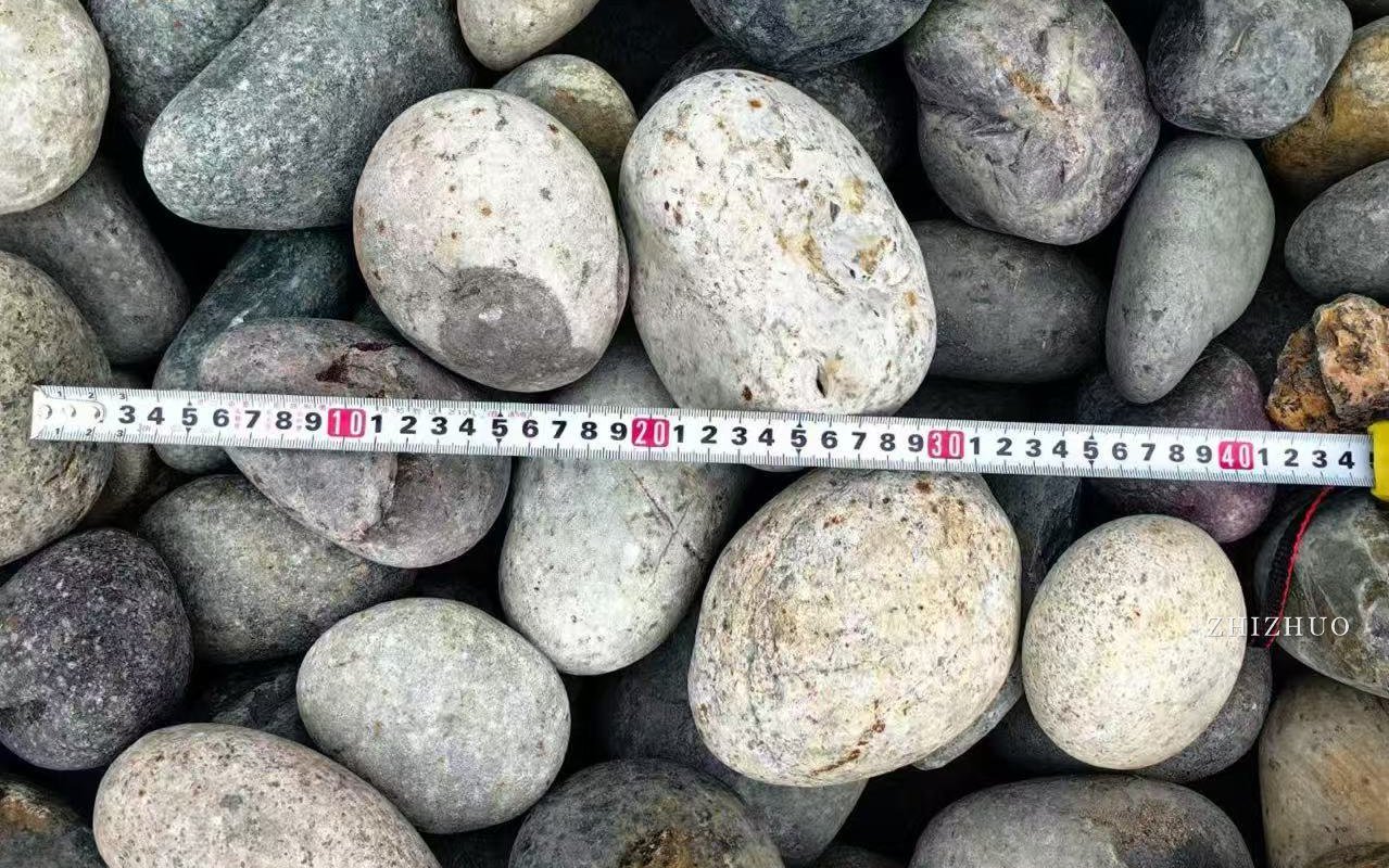 Mixed natural river stones with a measuring tape laid across them