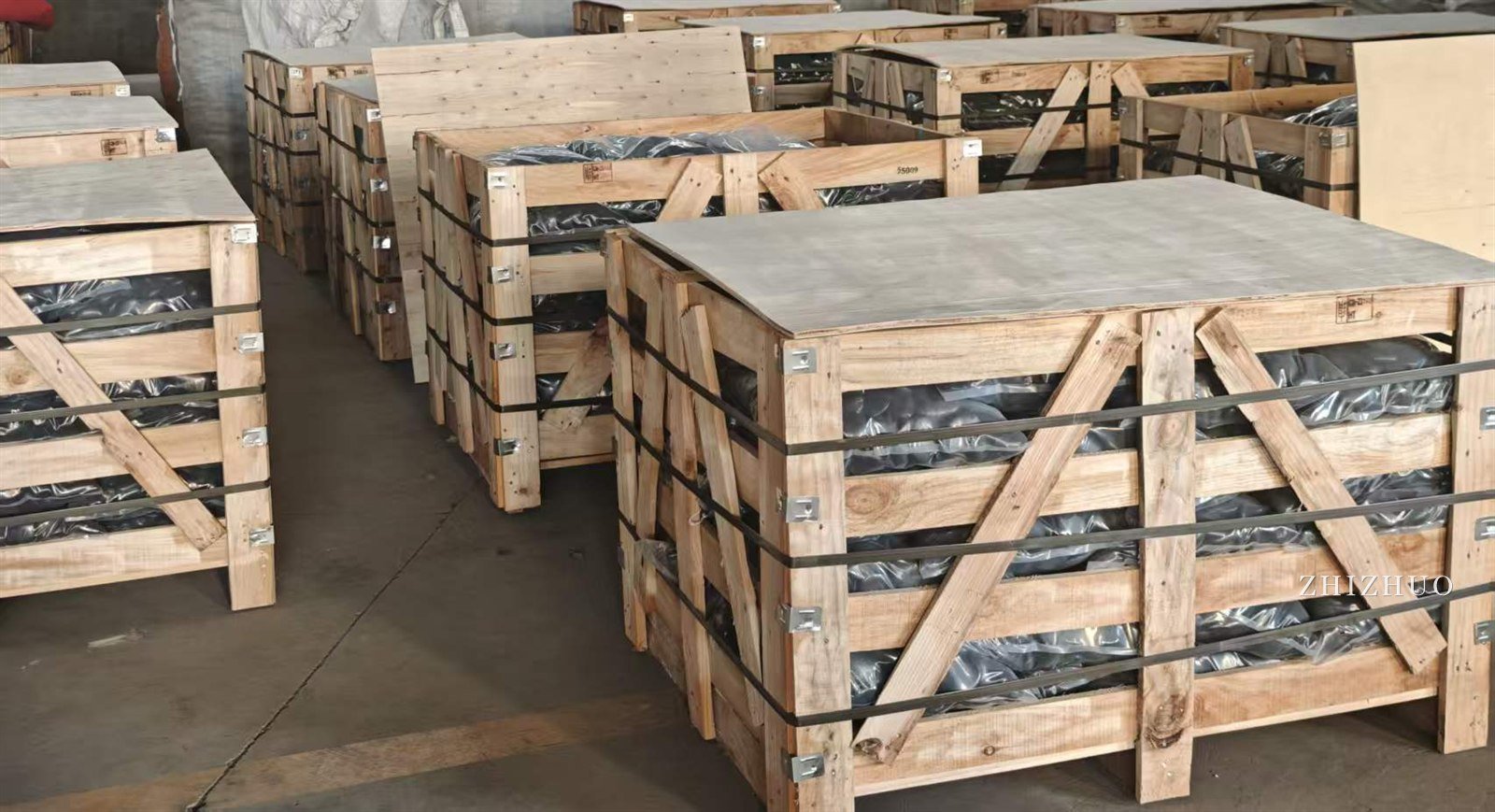 Wooden export crates of bagged black pebbles, strapped and ready to load, in the warehouse