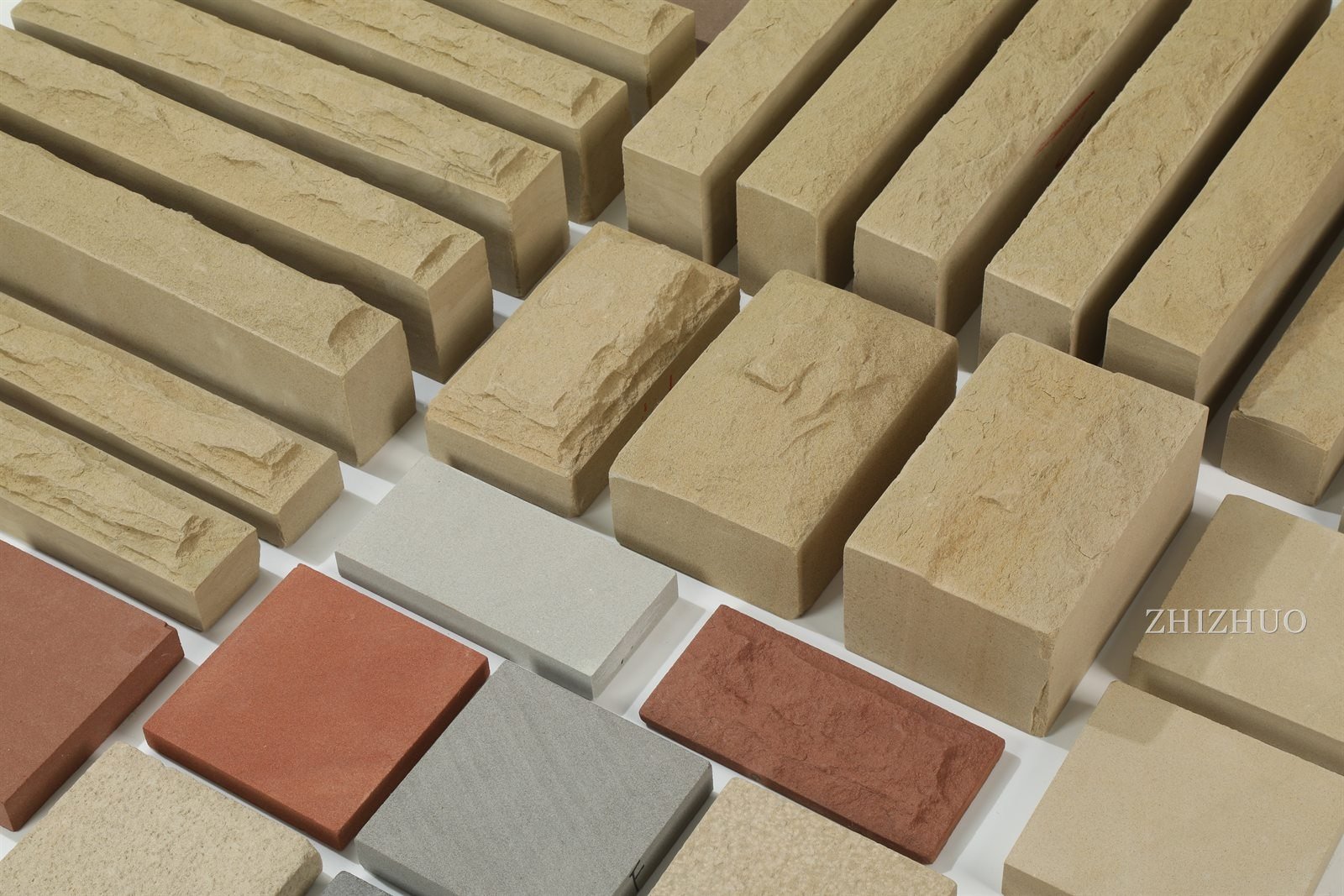 Beige sandstone walling bricks, strips and coloured tiles, close-up